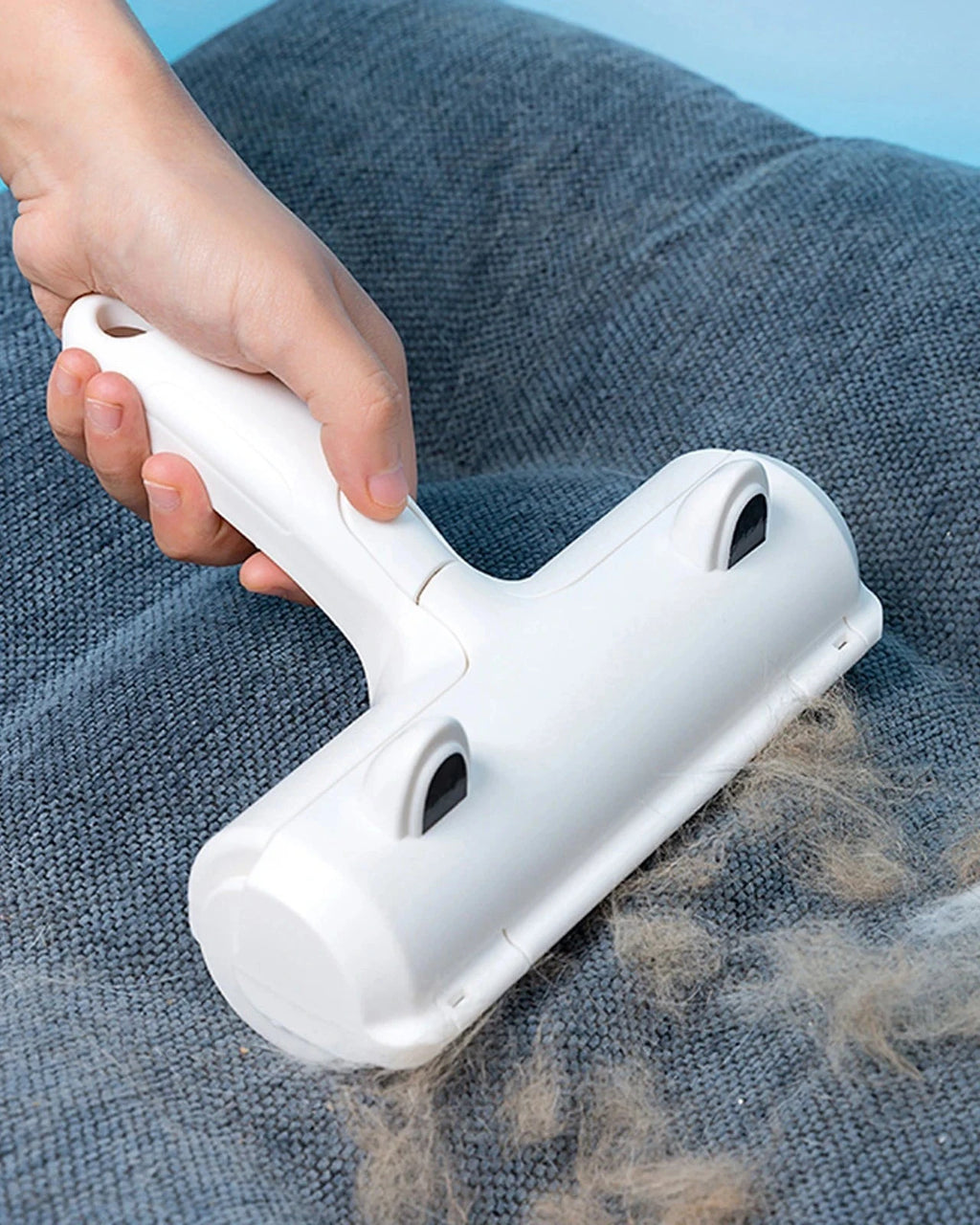 The Aftermath Hair Remover rolling fur off a blue sofa cushion